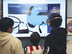 three students look at a screen demonstrating overcharge in a hoverboard