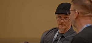 Travis Koupal is shown speaking to another educator fellow, wearing a gray shirt and black hat